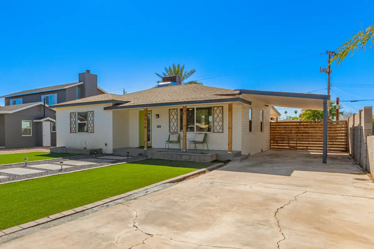 The front yard features artificial grass and inviting porch seating, with decorative windows adding historic charm. The setting captures neighbors socializing, children enjoying the outdoors, and a welcoming atmosphere under the stars.