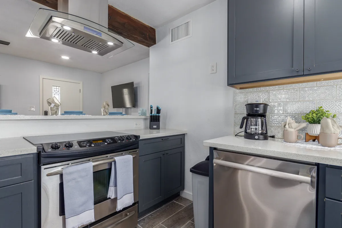 A close-up view of the kitchen's stainless steel appliances and granite countertop, with a decorative backsplash and a coffee maker set out for use. Kitchen accessories and thoughtful details give the space a cozy, lived-in feel, ideal for both cooking and enjoying quiet coffee moments.